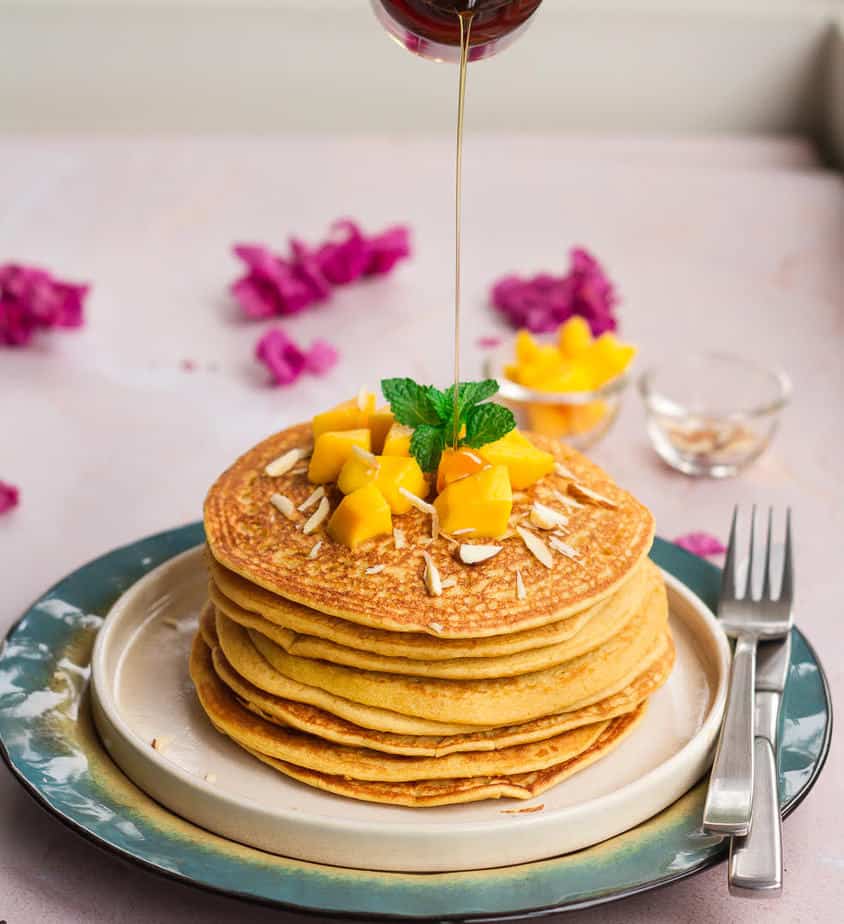 A stack of mango pancakes with a drizzle of maple syrup.