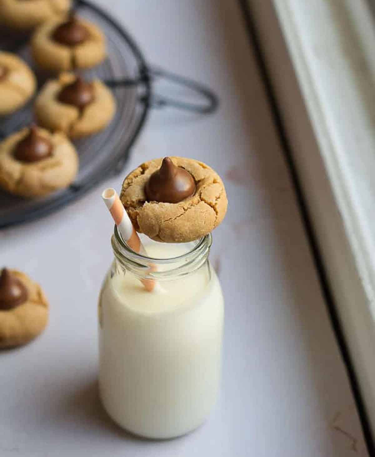 peanut butter cookie on a bottle of milk with a straw.