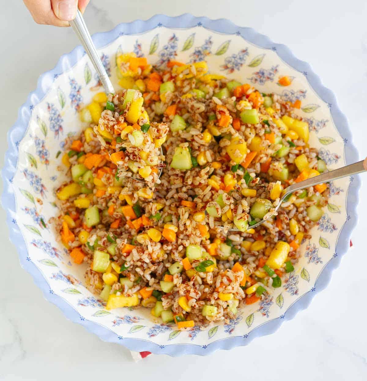 2 spoons mixing the salad in a large bowl.
