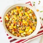 A bowl of rice and mango salad on a red and white napkin.
