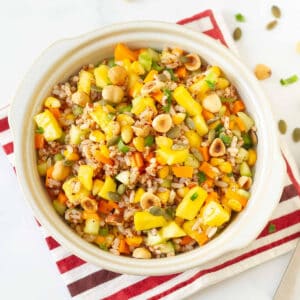 A bowl of rice and mango salad on a red and white napkin.