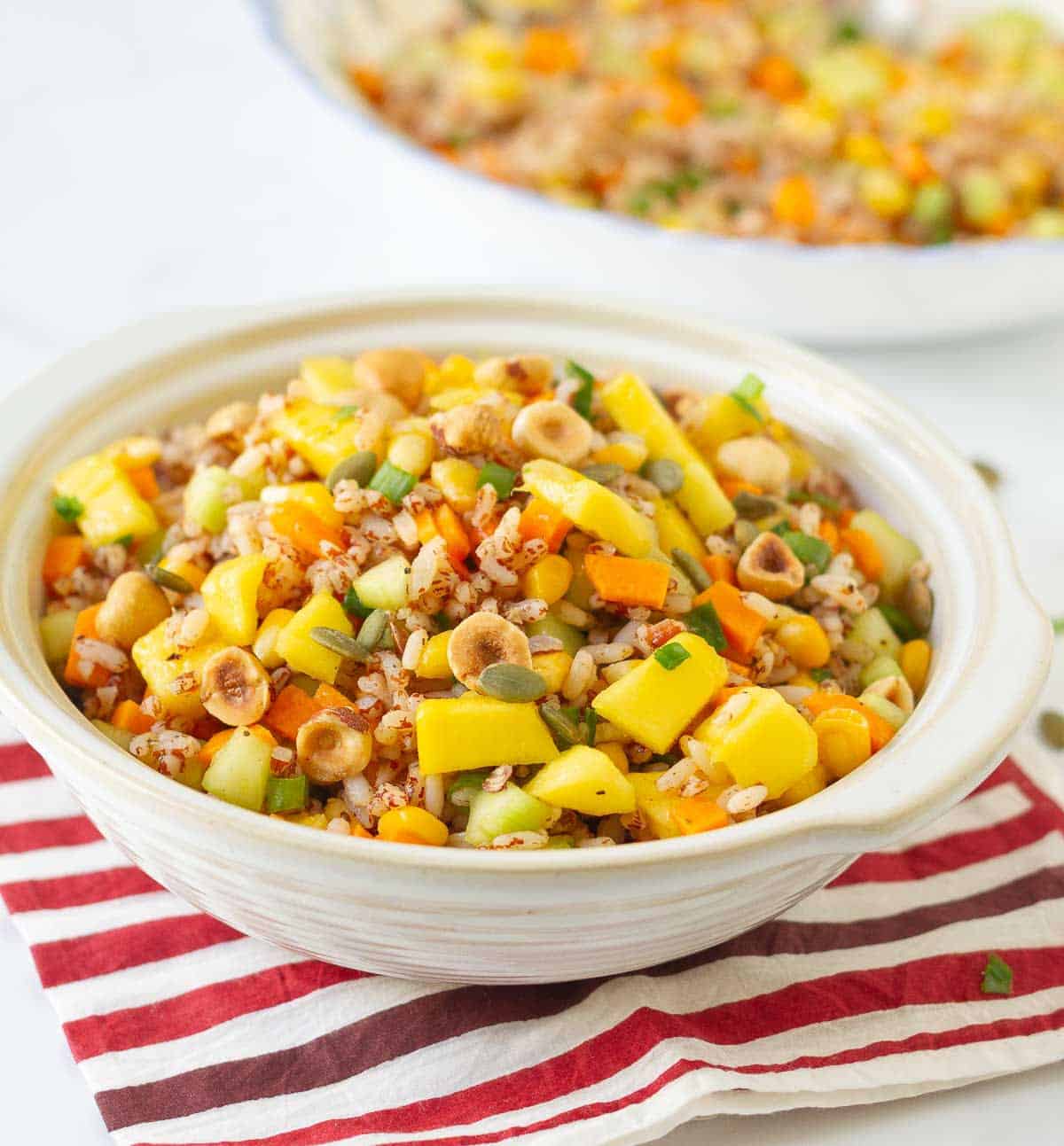 A bowl of rice salad with mango and veggies.