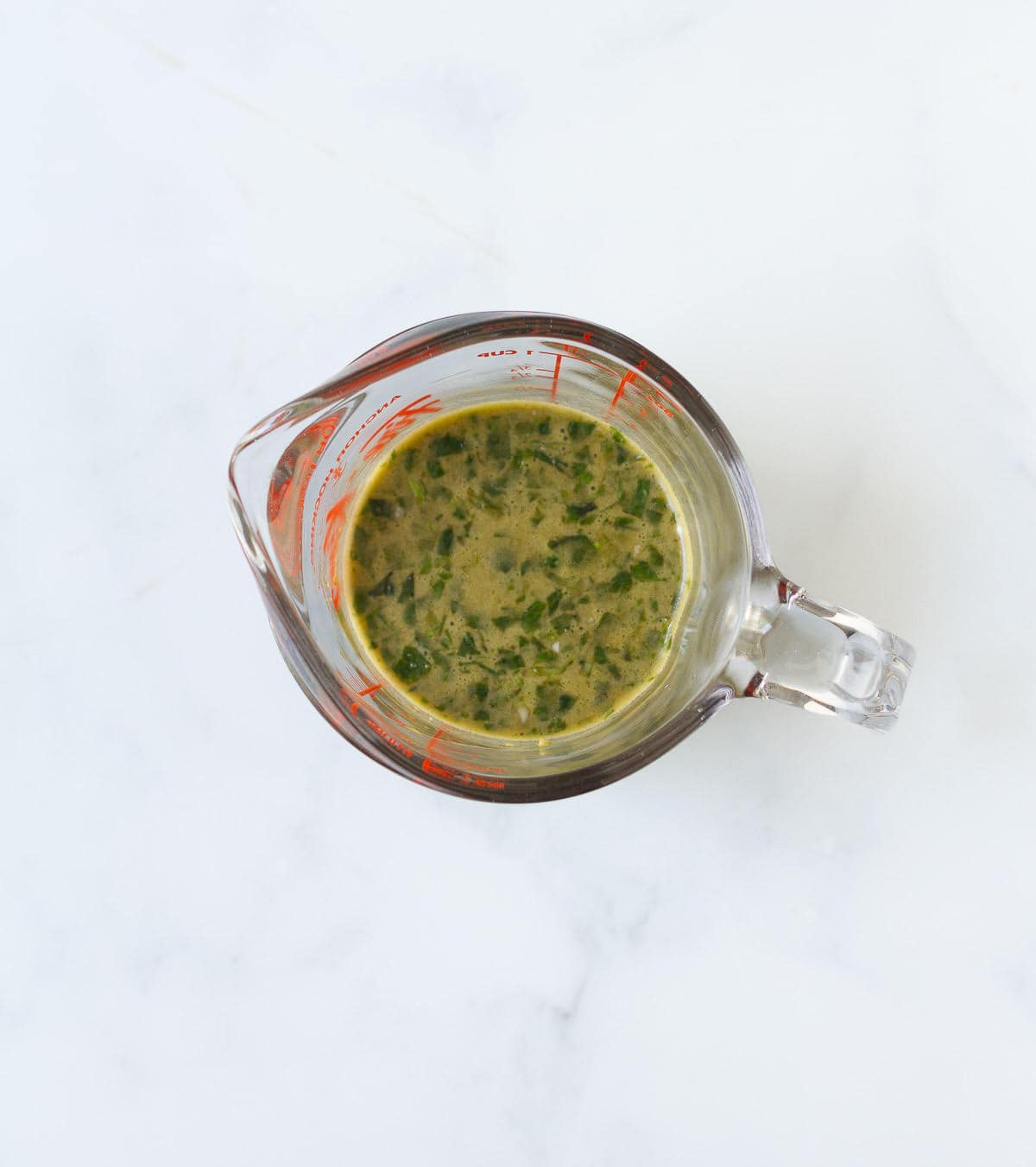 Basil vinaigrette in a small measuring cup.