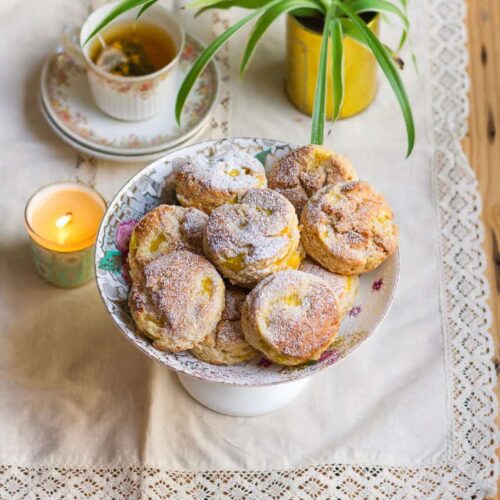 scones on a cake stand with a candle, tea and plant in the background.