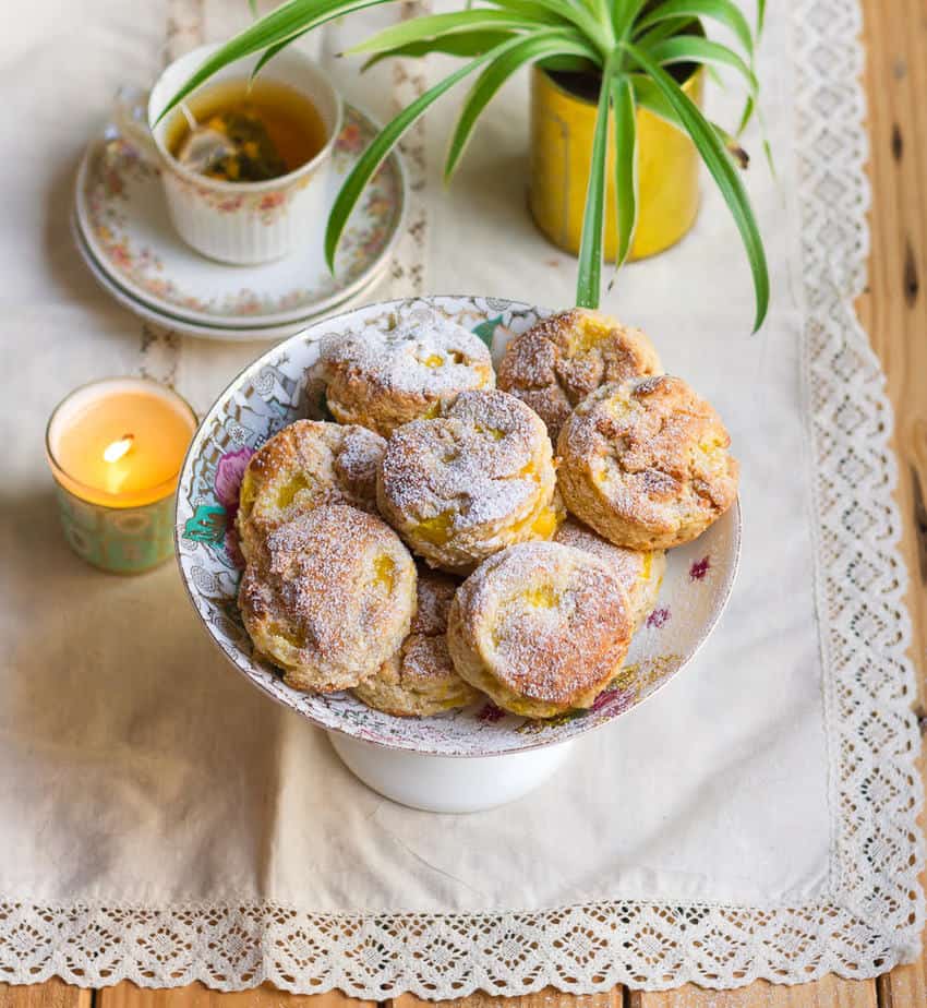 scones on a cake stand with a candle, tea and plant in the background.