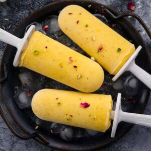 3 mango popsicles on a iced filled tray.