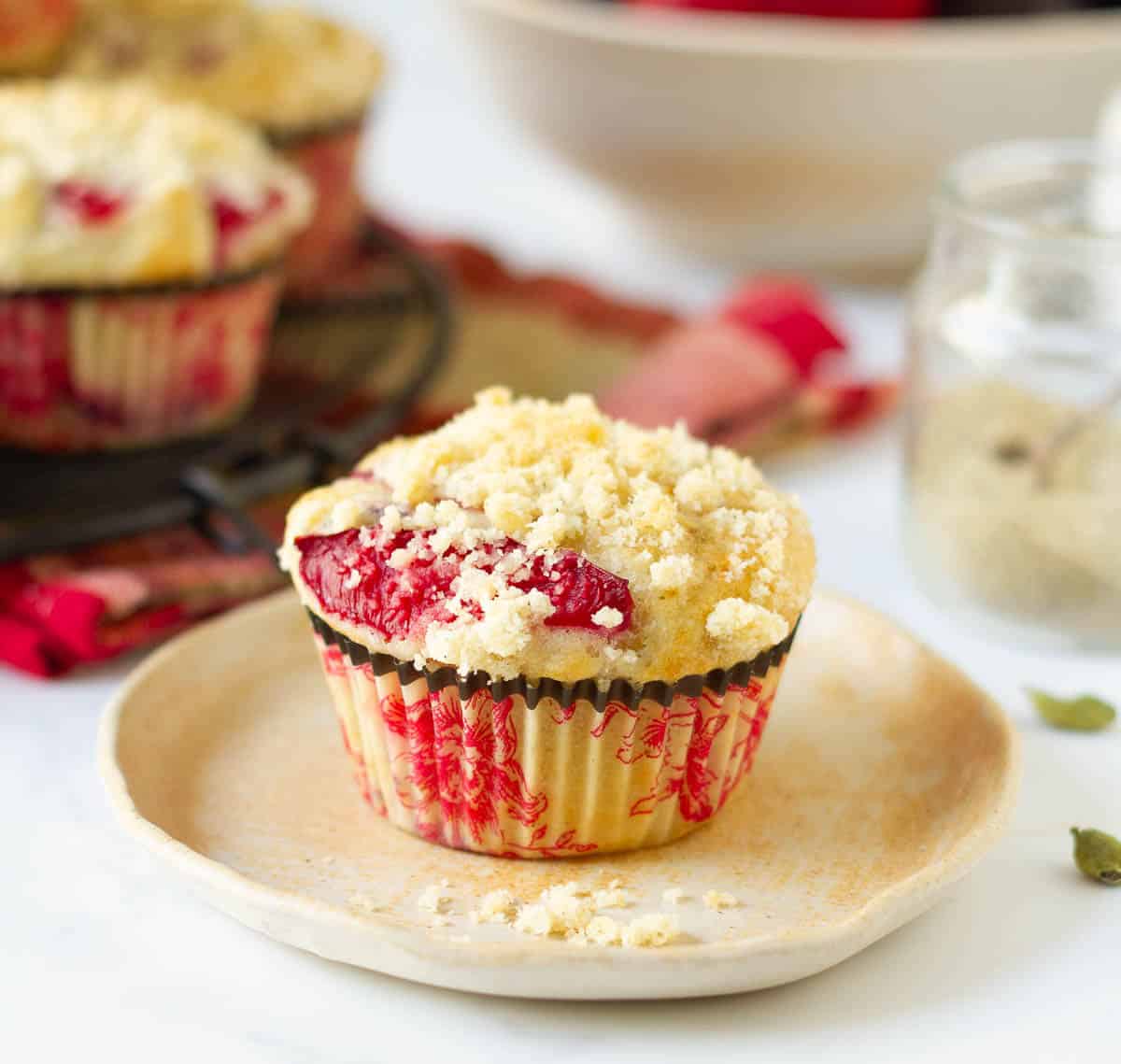 A plum muffin with streusel on a plate.