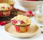 A plum muffin with streusel on a plate.