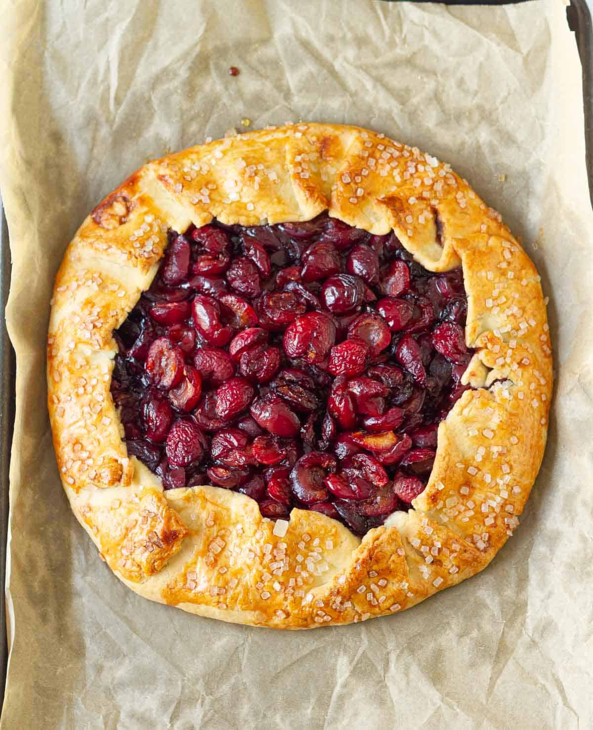 Baked cherry galette on parchment paper.
