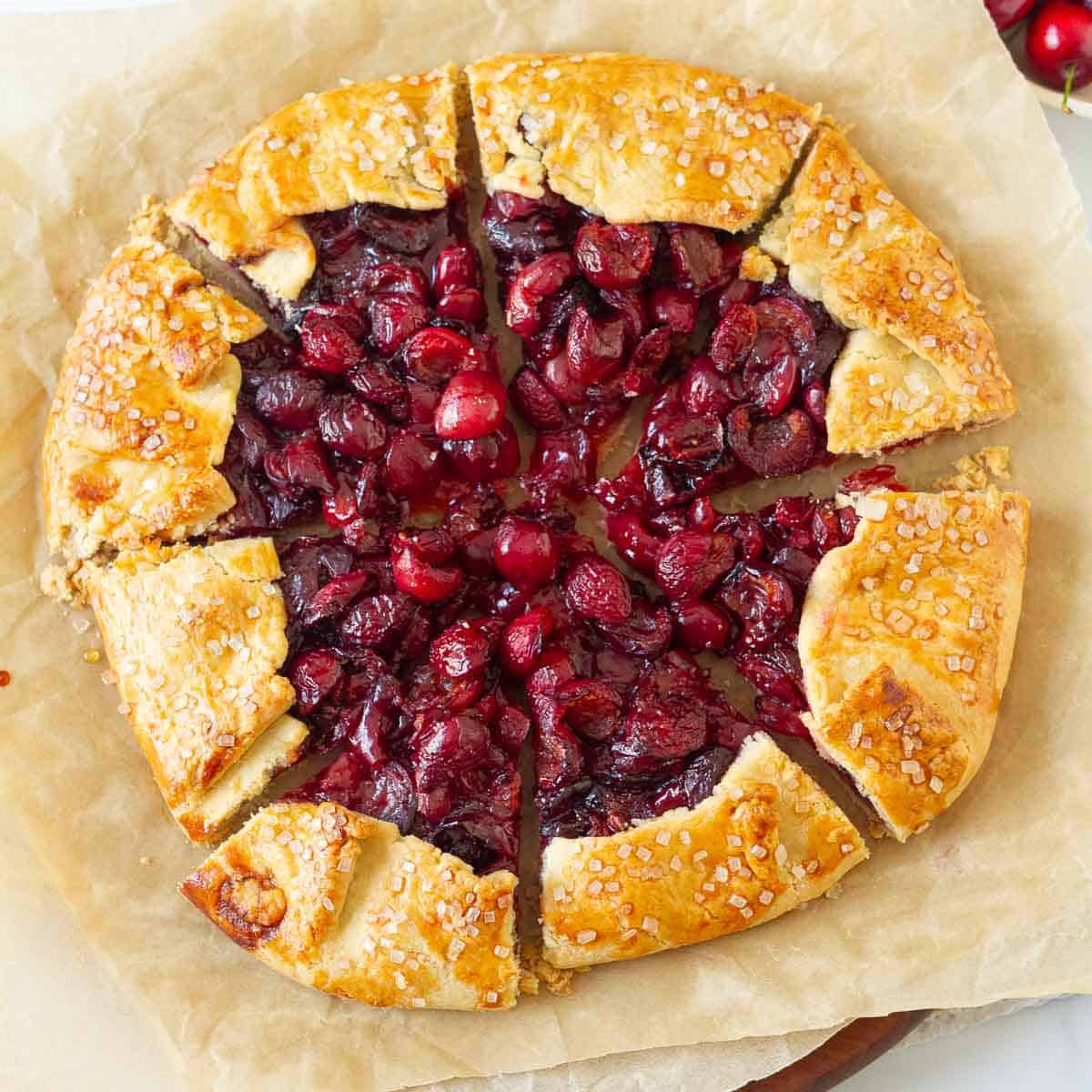 Cherry galette cut into 8 slices on parchment paper.