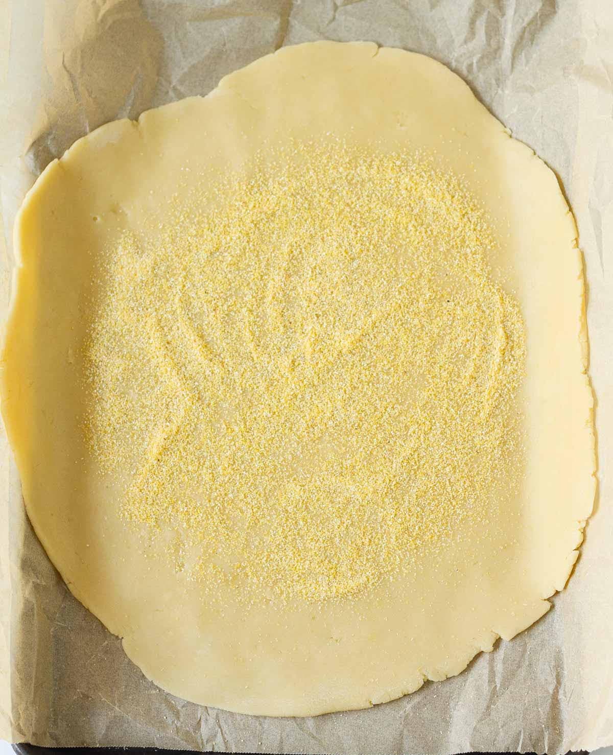 Rolled out pastry dough sprinkled with polenta on top.