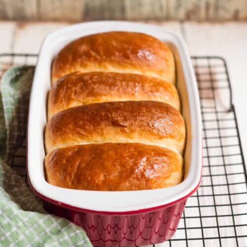 Eggless Brioche in a red loaf pan on a wire rack.
