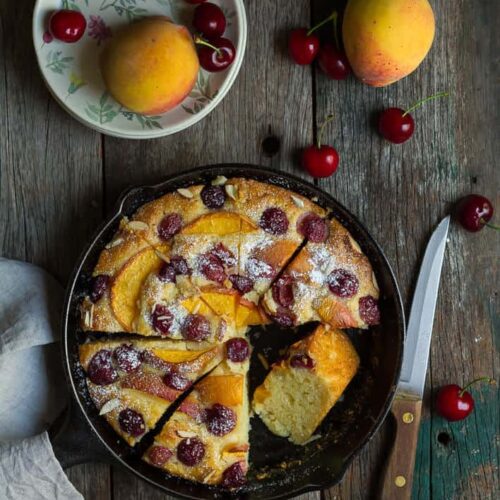 Peach Cherry Cake in a skillet with 1 slice kept sideways.