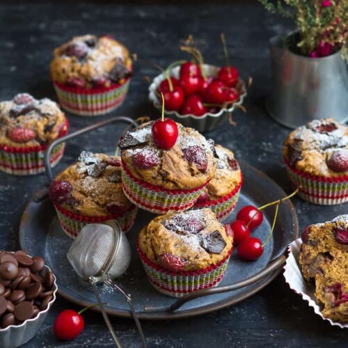 Muffins with cherries and chocolate on a small gray plate.