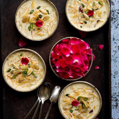 Sheer Khurma in 4 dessert bowls on a tray with a bowl of rose petals.
