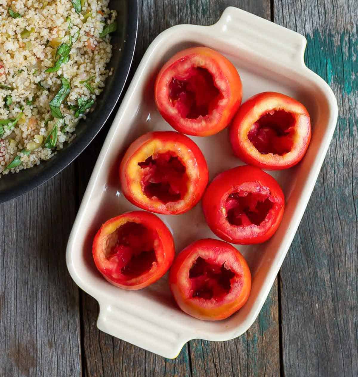 6 hollowed-out tomatoes in a baking dish.