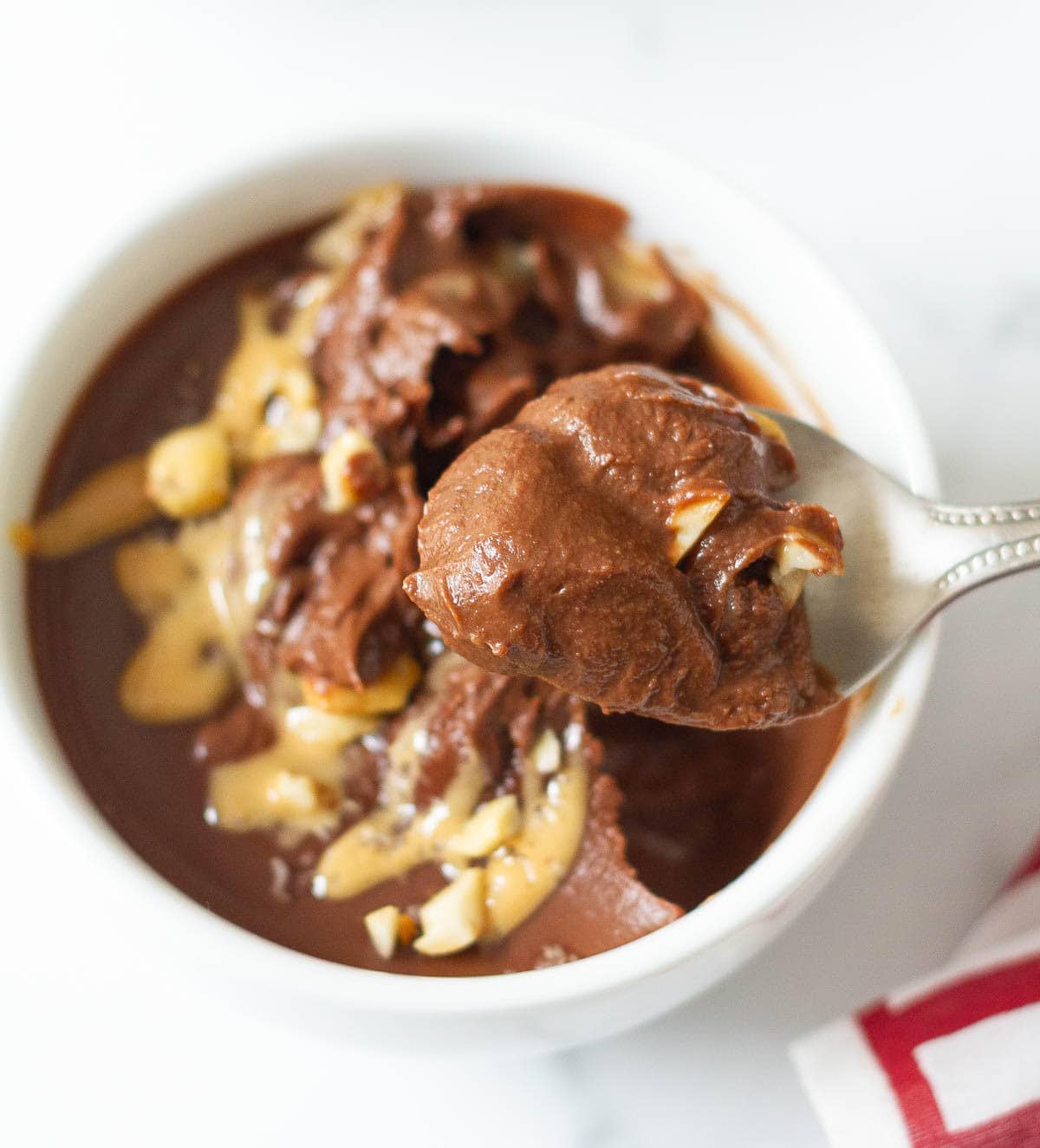 A spoonful of chocolate pudding on top of the pudding bowl.