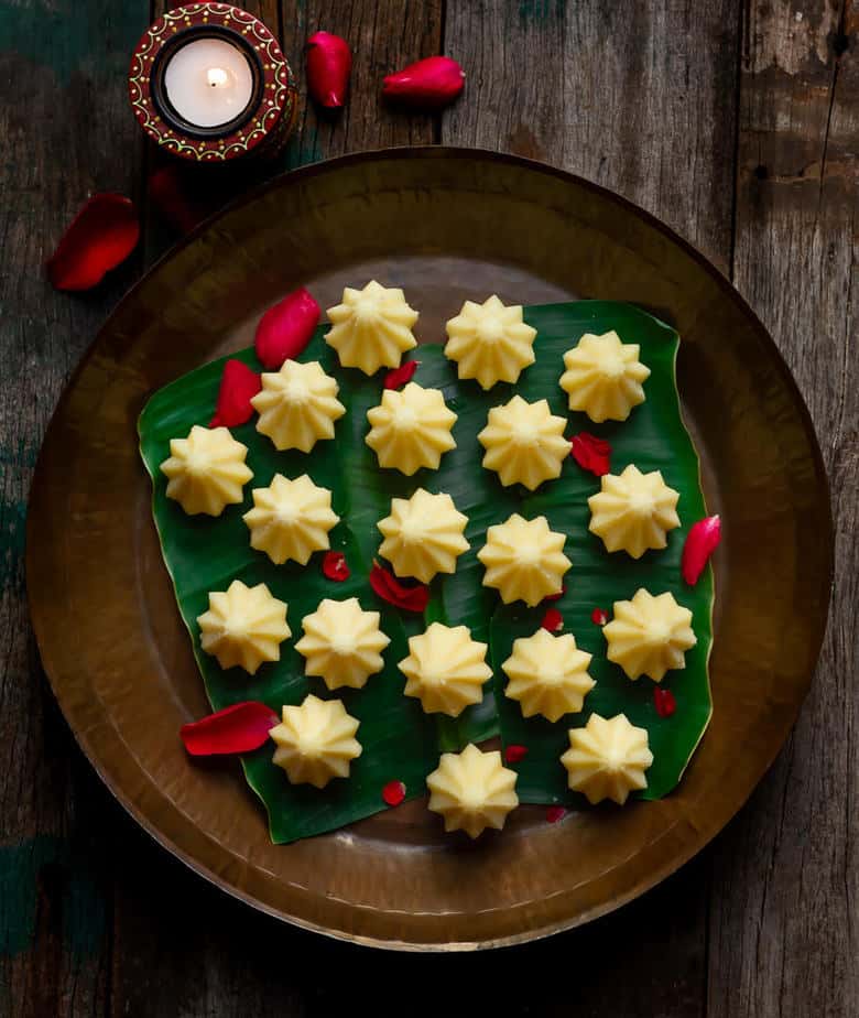 Coconut Mawa Modak in a brass platter on a banana leaf.