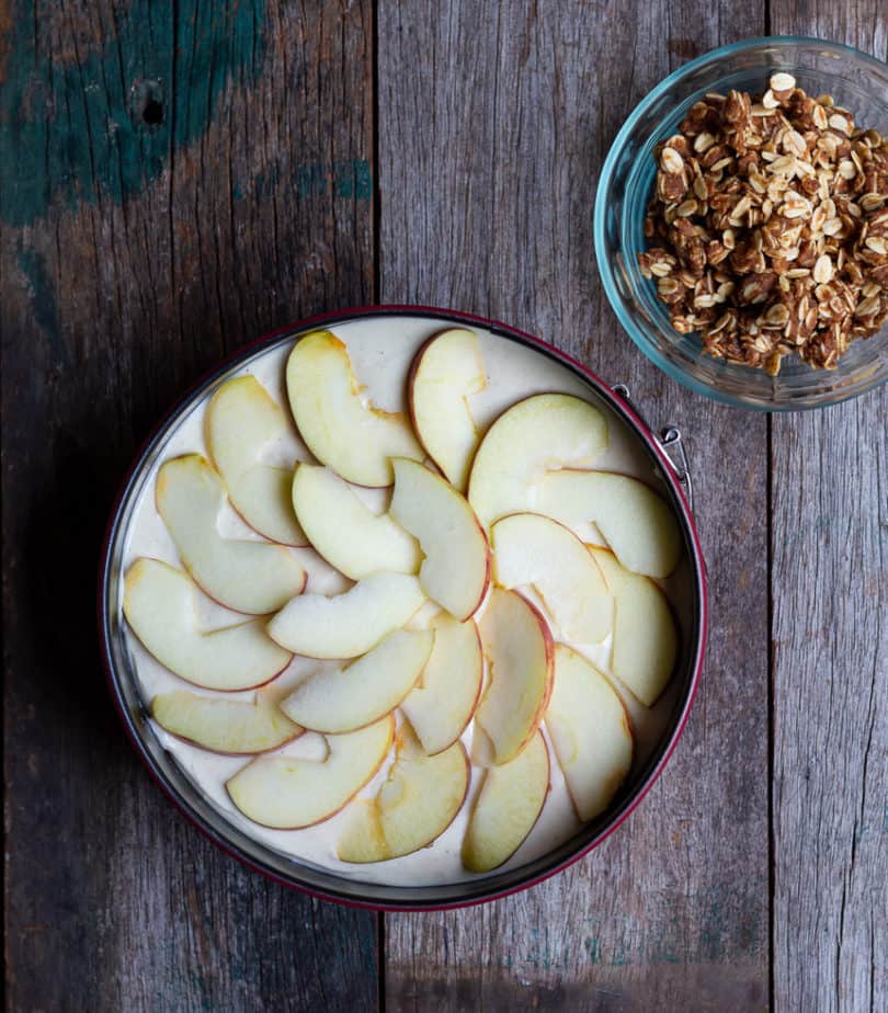Sliced apples arranged on top of cheesecake batter.