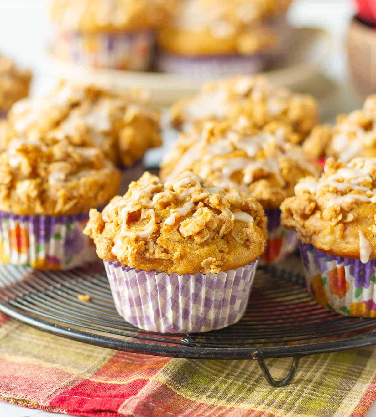 Apple muffins with streusel and glaze on a wire rack.