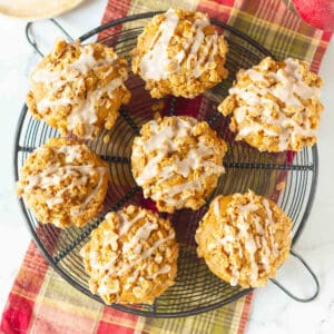 7 Peanut butter apple muffins with cinnamon glaze on a round wire rack.