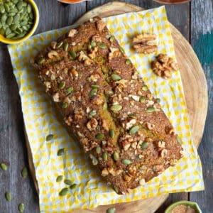 Pumpkin bread on a yellow napkin on a wooden board.