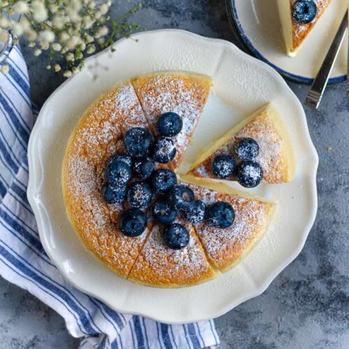 Cheesecake cut into slices and topped with blueberries.