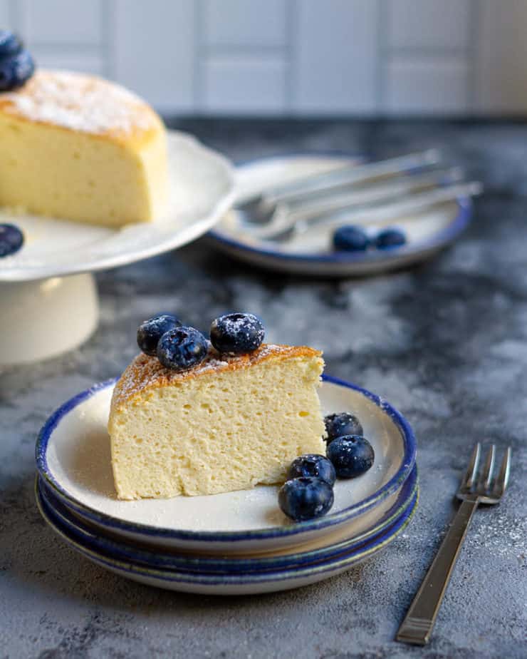 A slice of cheesecake with blueberries on top on a plate.