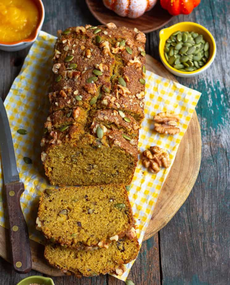 Sliced pumpkin bread with a knife on a wooden board.