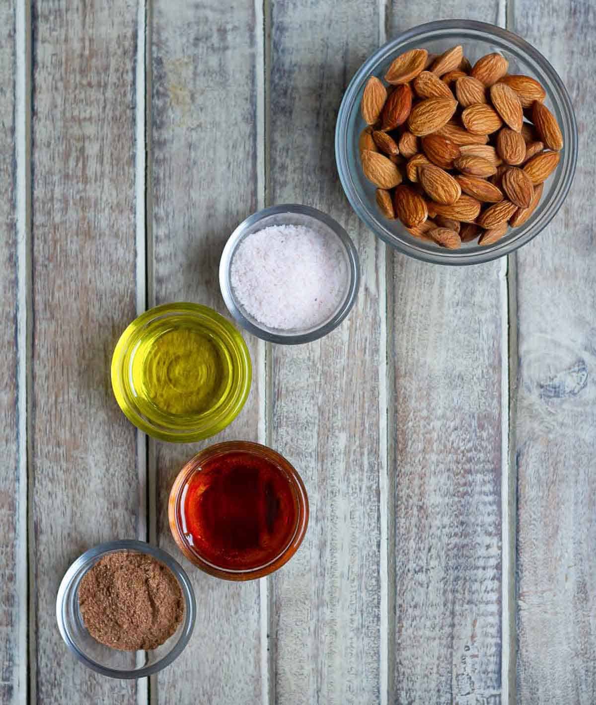 Ingredients for making pumpkin spiced almonds in small bowls.