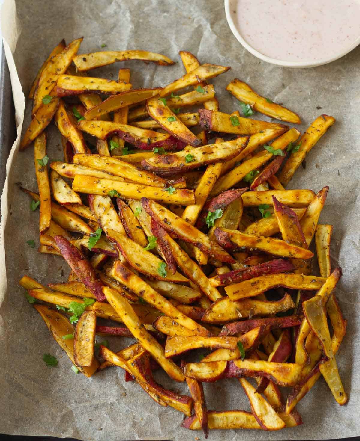 Sweet potato fries on parchment paper with a dip.