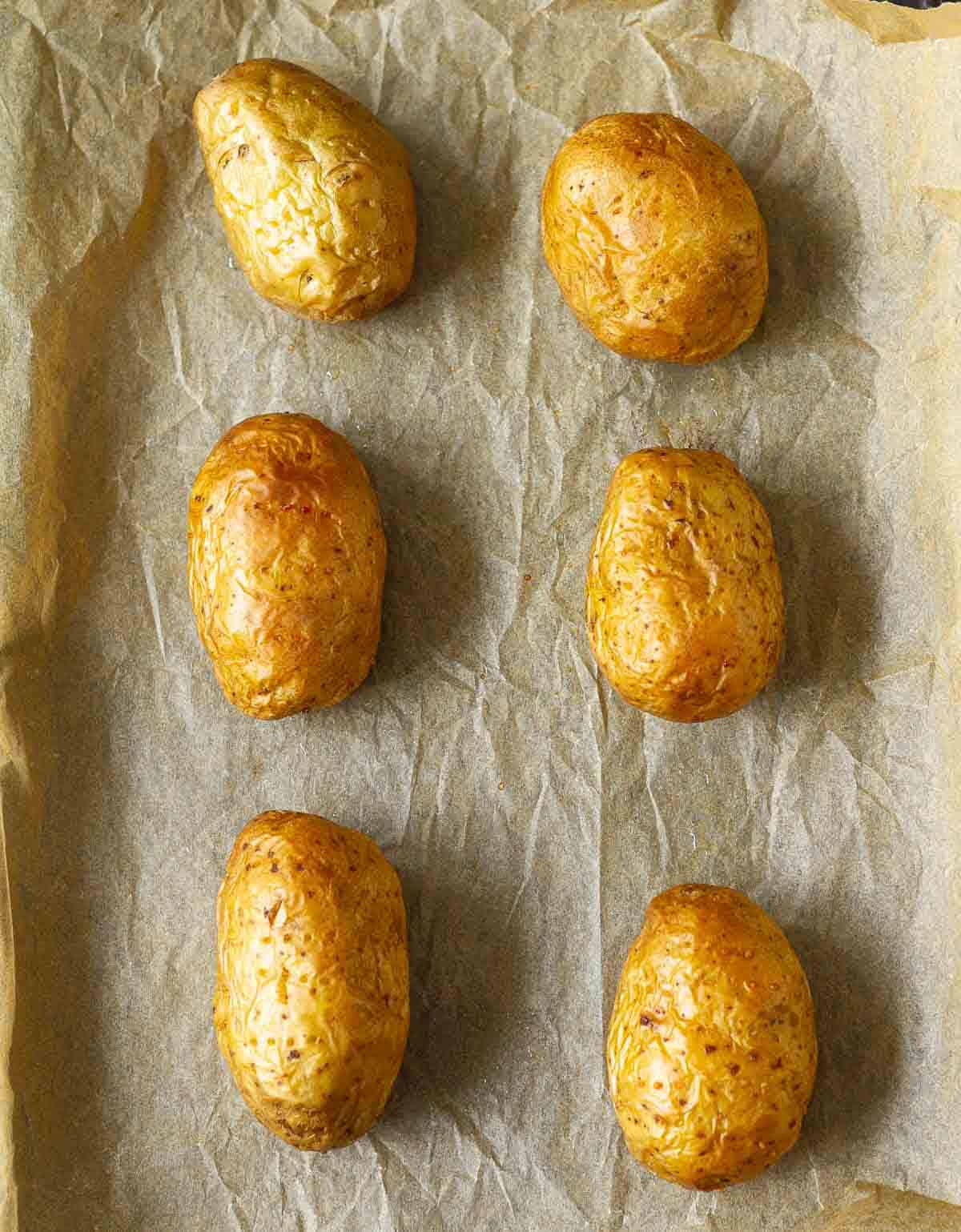 Baked potatoes on parchment-lined baking tray.