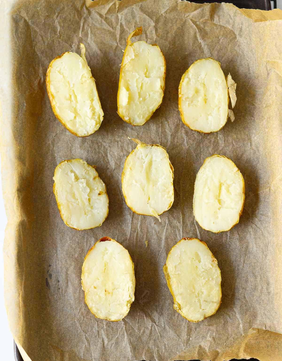 Baked potatoes cut in half on a baking tray.