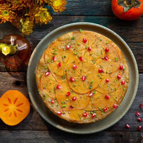 Upside-Down Persimmon Cake on a platter with fall decor around.