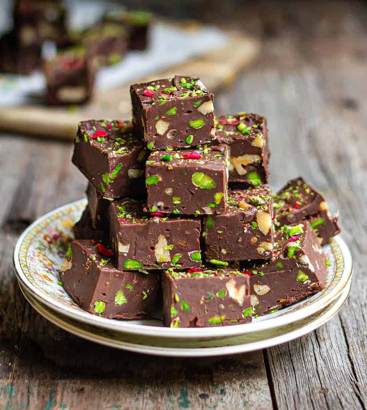 chocolate fudge squares stacked on a plate.