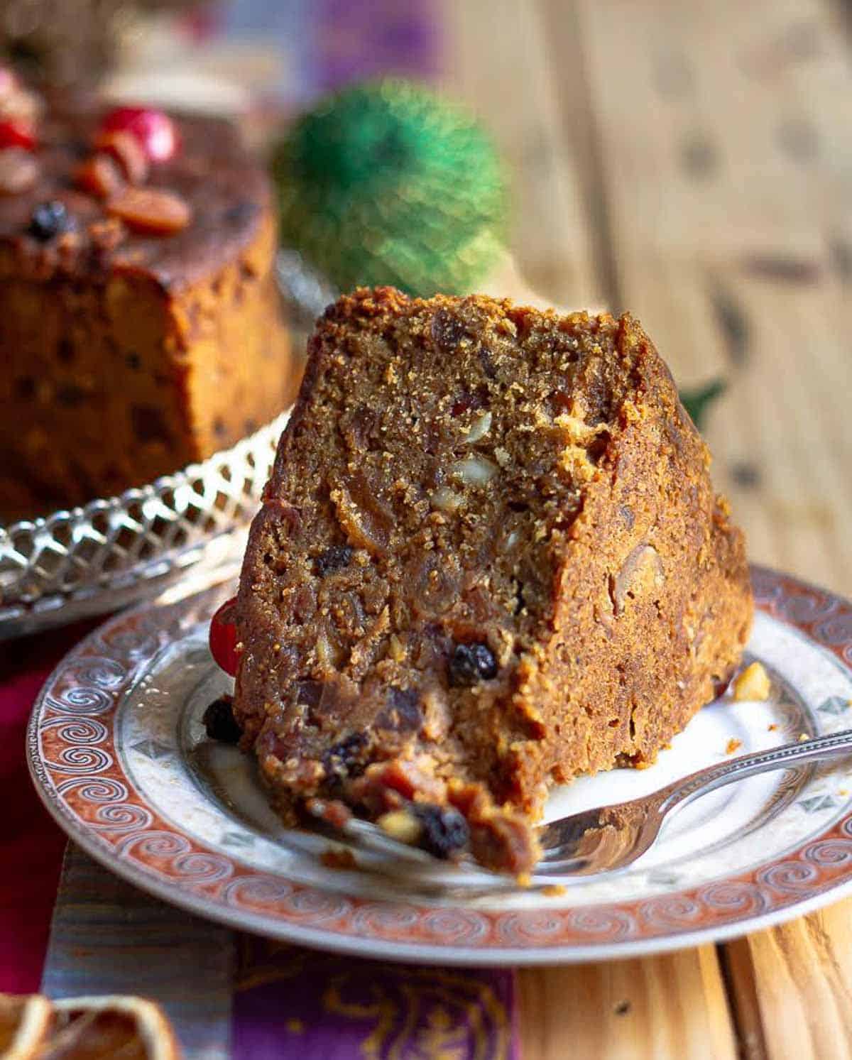 a slice of christmas rum fruit cake on a small plate with a fork.