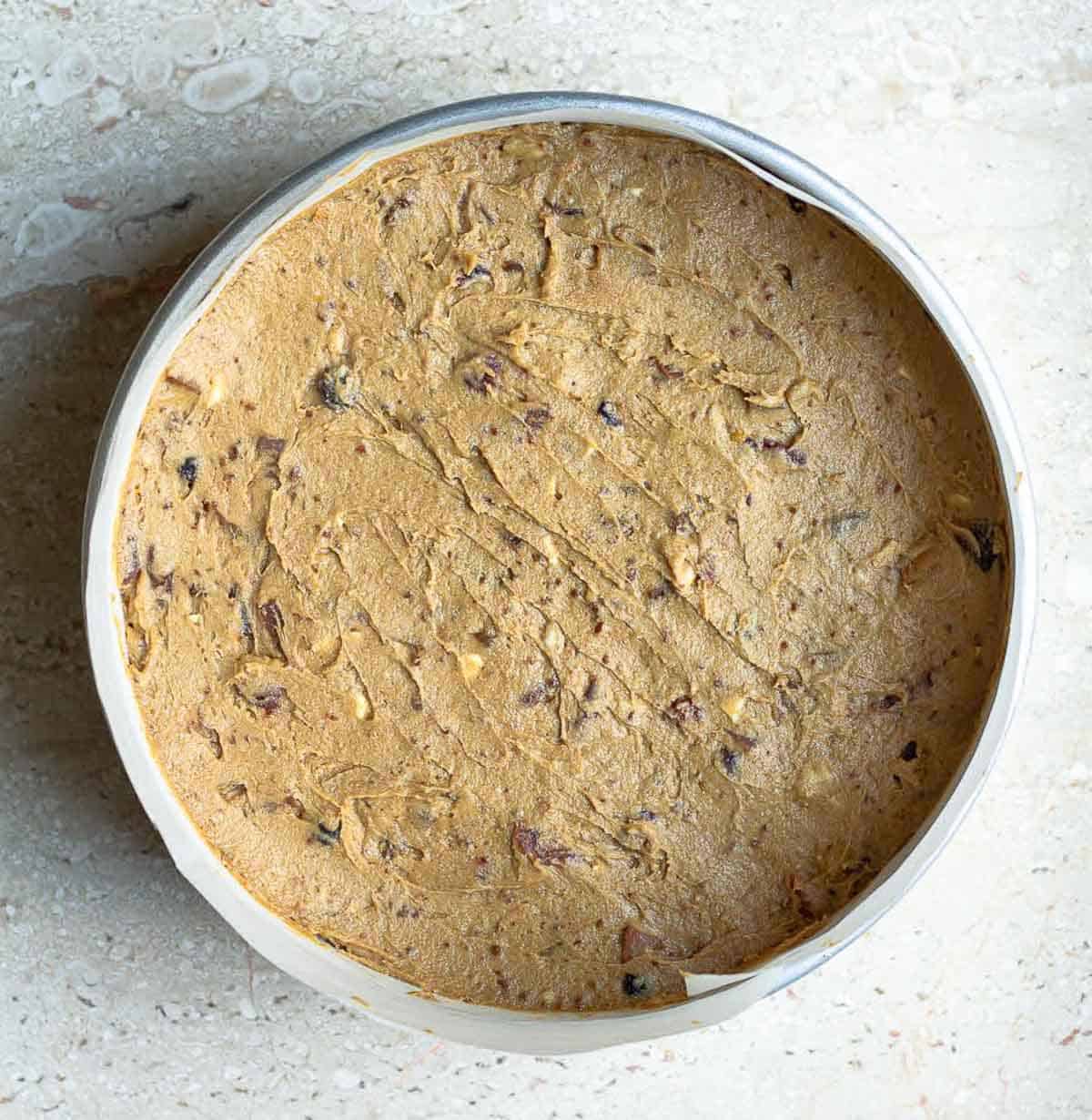 cake batter in a parchment paper lined round cake tin.