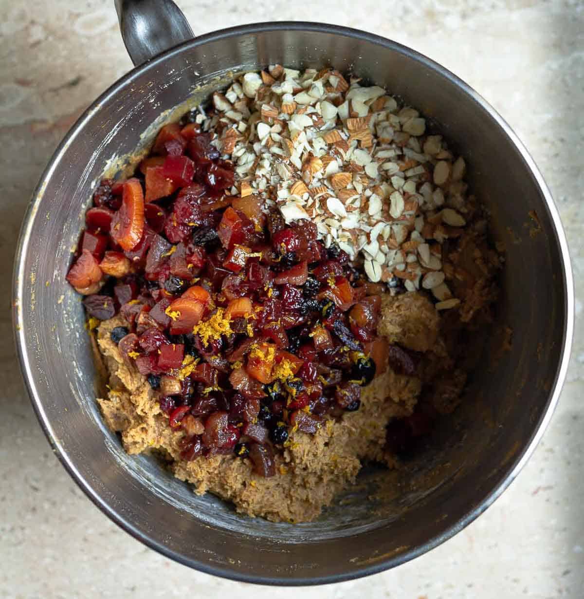 nuts ans soaked fruits on top of cake batter in a mixing bowl.