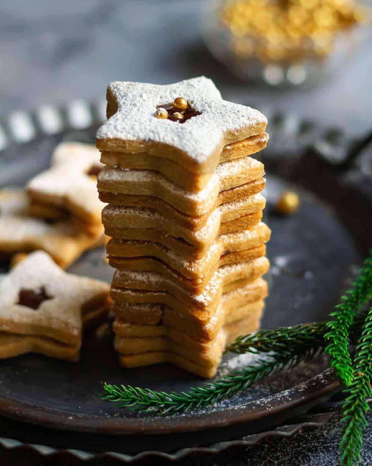 star shaped linzer cookies stacked up on a metal serving tray.