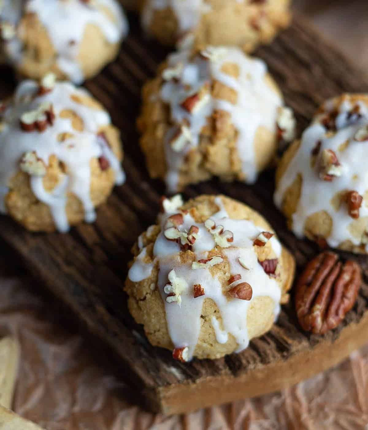 Cookies with maple glaze and pecans on a wooden board.