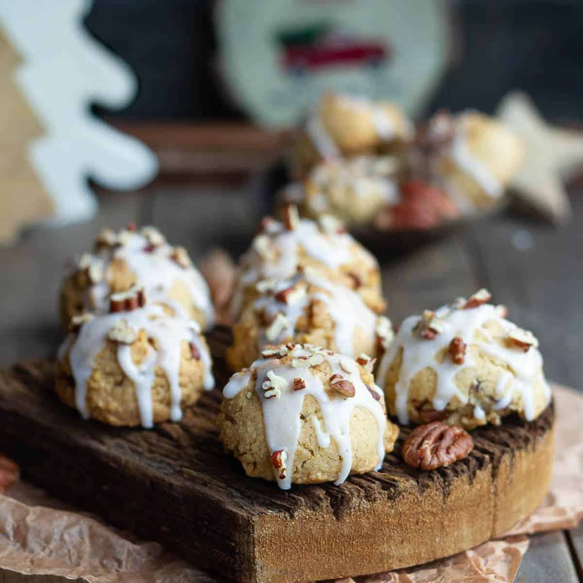 cookies with glaze and pecans on a wooden board.
