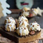 Glazed cookies on a wooden board with christmas decor around.