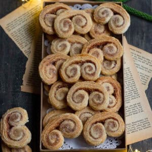 French heart cookies in a small tray on a wooden board with old papers.