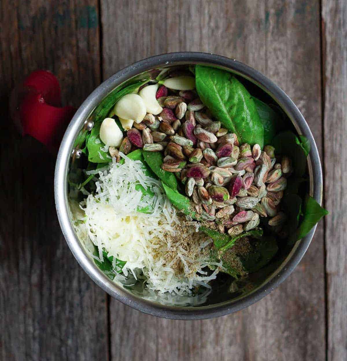 Basil, garlic, pistachio, and cheese in a blender jar.