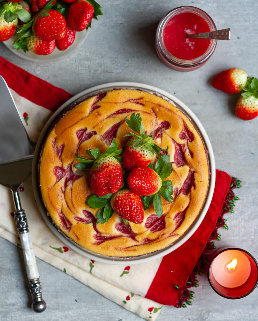 Strawberry cheesecake on a serving plate with strawberry sauce and strawberries on the side.