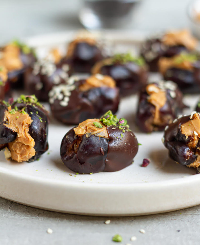 Peanut butter stuffed dates with chocolate and nuts on a plate.