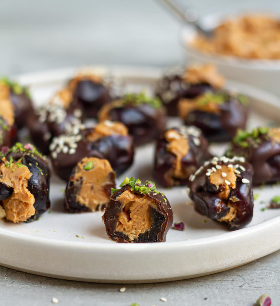 Stuffed dates on a plate with one date cut in half to show the inside.