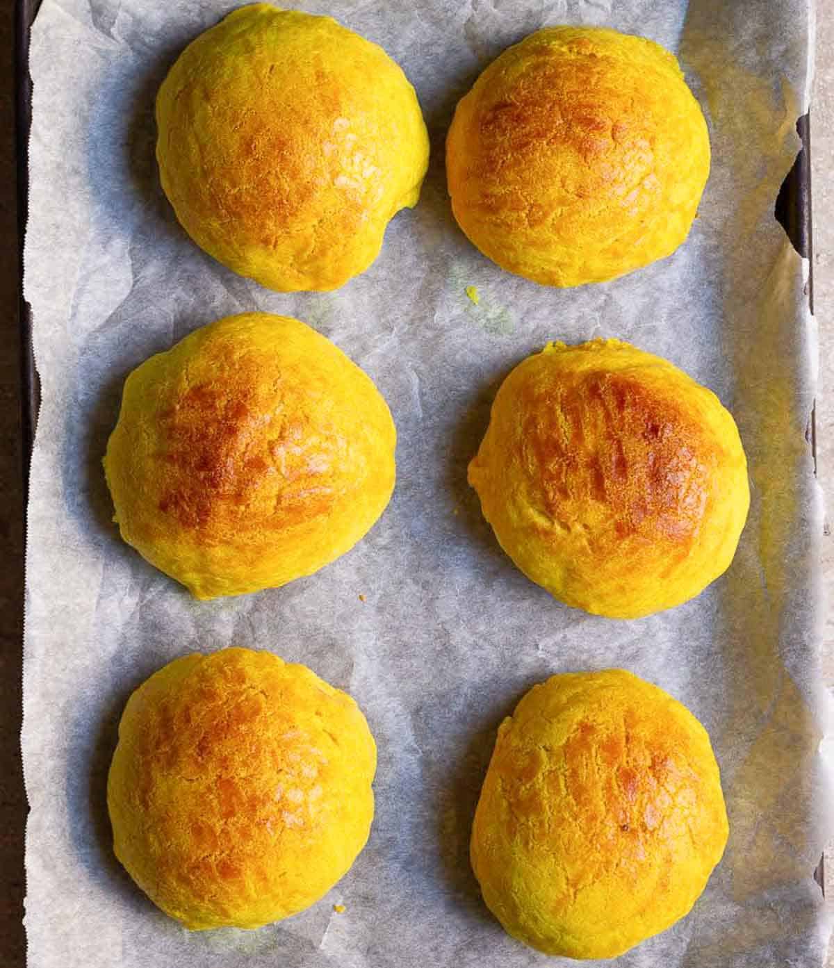 Baked pineapple buns on a tray lined with parchment paper.