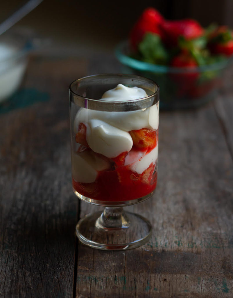 Assembled strawberry tiramisu with layers of mascarpone cheese and strawberry soaked ladyfingers in a glass.