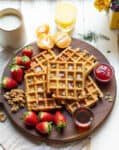 Carrot cake waffles with maple syrup on a wooden board.